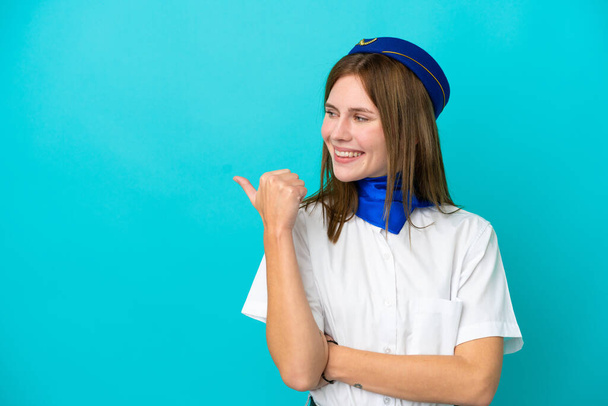 Літак стюардеса Англійська жінка ізольована на синьому фоні, вказуючи на бік, щоб представити продукт - Фото, зображення