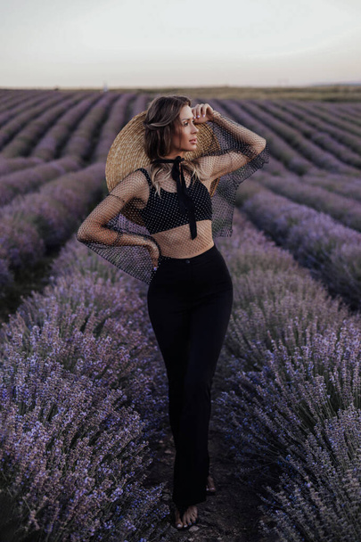 fashion outdoor photo of beautiful woman with dark hair in elegant dress posing in blooming lavender field on sunset time - Photo, Image
