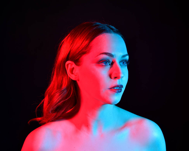 Nahaufnahme Porträt der schönen Frau Modell, mit rosa und blauen Neon-Beleuchtung im Studio mit dunklem Hintergrund. - Foto, Bild