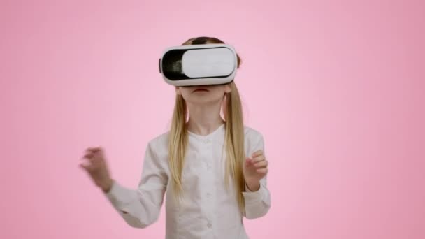 Tecnologias modernas e educação. Estúdio tiro de menina bonito vestindo óculos VR desfrutando de realidade aumentada, jogando jogo ou assistindo aula, fundo rosa, câmera lenta - Filmagem, Vídeo
