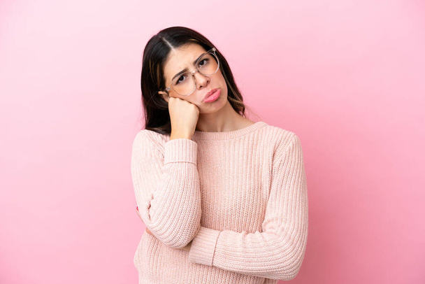 Young Italian woman isolated on pink background With glasses and with sad expression - Photo, image