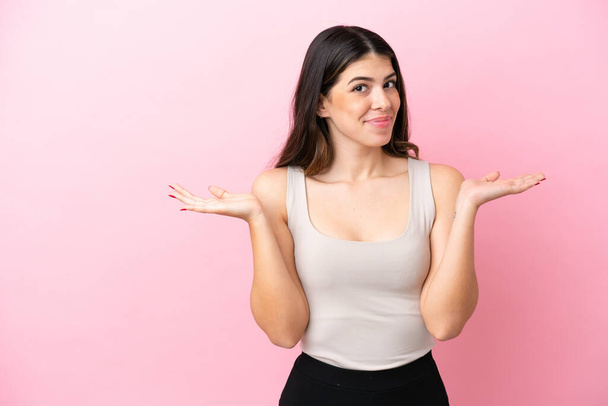 Junge Italienerin auf rosa Hintergrund isoliert mit Zweifeln beim Händeheben - Foto, Bild