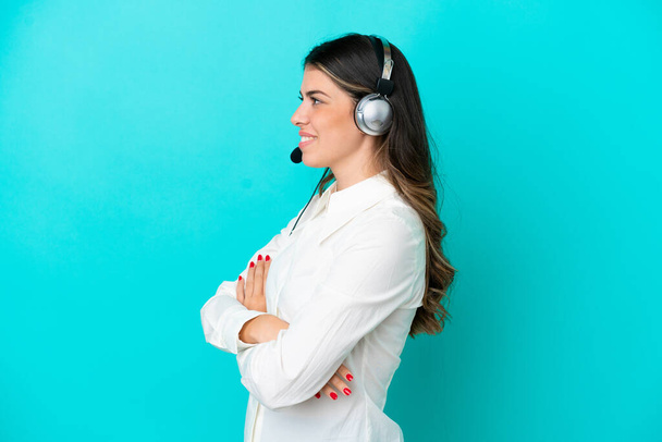 Telemarketer Italian woman working with a headset isolated on blue background in lateral position - Photo, Image