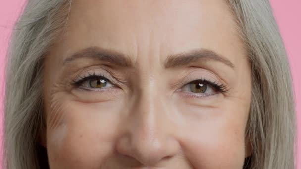 Mądrość starszych ludzi. Zbliżenie zdjęcia nierozpoznawalnych szczęśliwych oczu starszej pani, pomarszczonej kobiety patrzącej w kamerę i uśmiechniętej, spowolnionej - Materiał filmowy, wideo