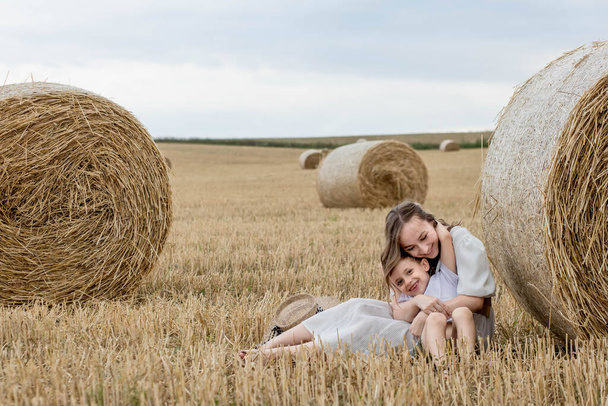 Young mother and her son are hugging near straw bales in a field. A happy family. Mother's day. - Foto, Bild