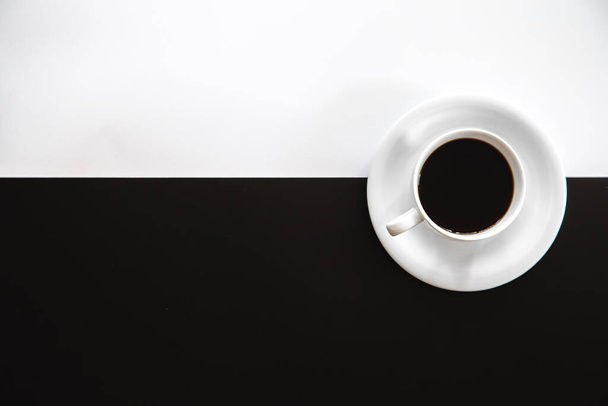 Cup of coffee on a black and white background, flat lay, conceptual minimalism. - Fotó, kép