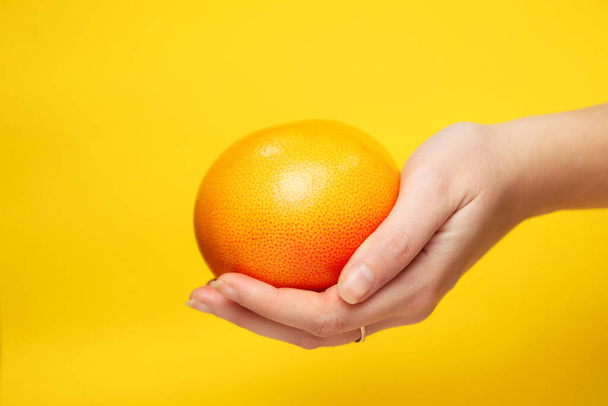 Defocus female hand holding while of a orange grapefruit. Healthy food concept. Fresh orange juice. Vegan, vegetarian concept. Banner with copy space. Out of focus. - Foto, Bild