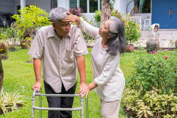 Yaşlı mutlu Asyalı adam yürüteç kullanıyor ve kızı ve karısıyla arka bahçede yürüyor. Bakıcının, birikimin ve sağlık sigortasının özenle mutlu emeklilik kavramı - Fotoğraf, Görsel