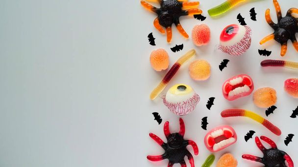 Close-up bright jelly candies,spiders,eyes,jaws,worms and bats,on white background,top view,flat lay,copy space.Decor concept for Halloween party,holiday treat,junk food.Pattern - Foto, Imagen