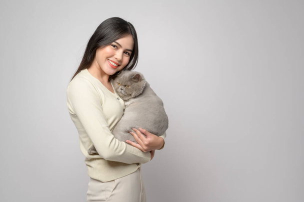 A young woman is holding lovely cat , playing with cat in studio on white background  - Foto, afbeelding