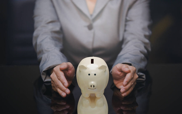 business woman holding hand around piggy bank, money safe and business management  - Φωτογραφία, εικόνα