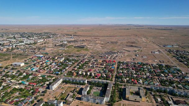 Balkhashin pikkukaupunki on näkymä lennokista. On uusia ja vanhoja taloja, leikkikenttiä rakennetaan. Autot ajavat maanteillä. Kaupunki keskellä aroa, mutta järven rannalla. - Valokuva, kuva