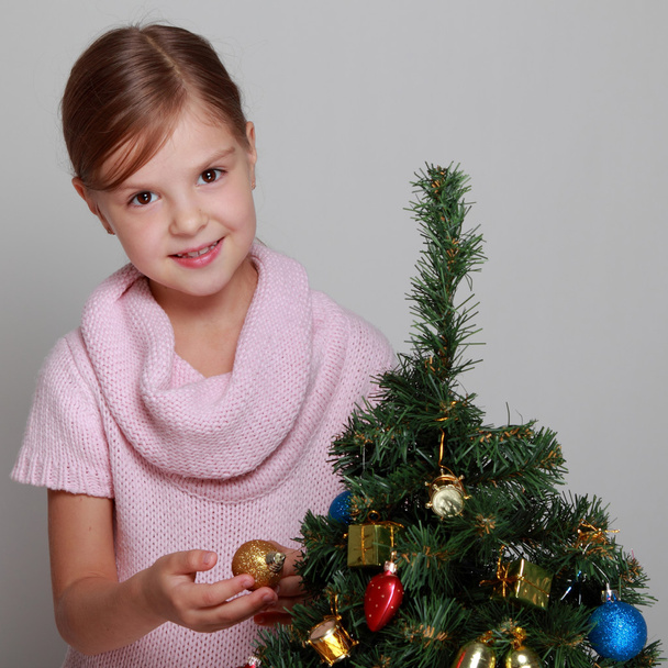 Criança perto de uma árvore de Natal decorada
 - Foto, Imagem