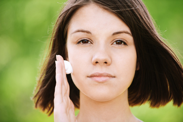 Молодая женщина наносит крем на лицо
 - Фото, изображение
