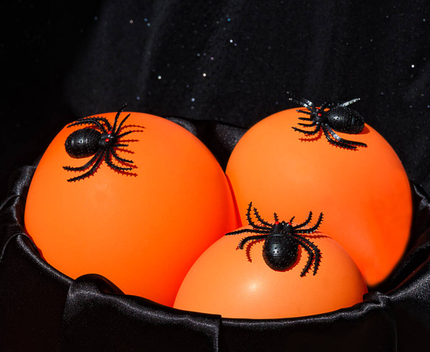 Halloween decor - lots of black spiders on an orange night light. On a black background, place for text. - Fotoğraf, Görsel