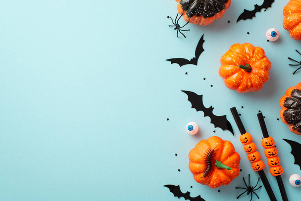Концепция вечеринки на Хэллоуин. Фото тыквы силуэты летучих мышей пауки многоножки глаза коктейль соломинки конфетти на изолированном пастельно-голубом фоне с копирайтом - Фото, изображение