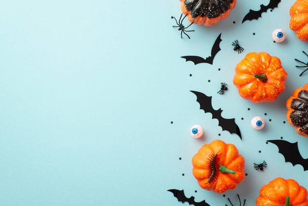 Halloween koncepció. Top view fotó kis sütőtök denevér sziluettek rovarok pókok százlábú hátborzongató szemgolyók és fekete konfetti izolált pasztell kék háttér üres hely - Fotó, kép