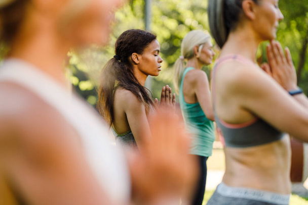 Multiracial women meditating during yoga practice in green park - Foto, immagini