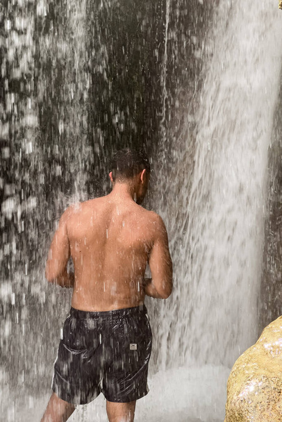 A man standing under a waterfall in Morocco - Photo, Image
