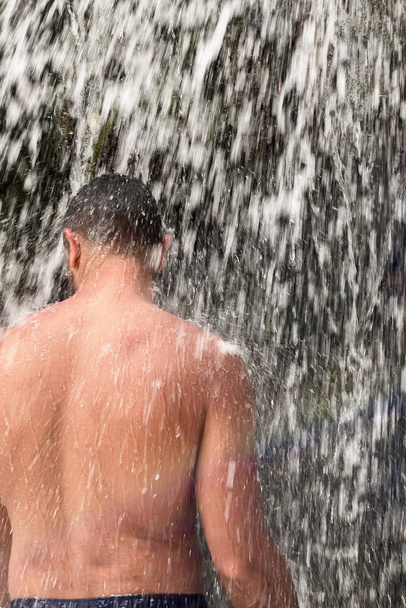 Чоловік стоїть під водоспадом у Марокко. - Фото, зображення