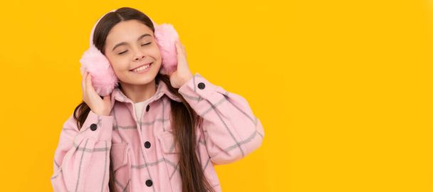 Warmth to touch. Happy child enjoy warmth of fur earmuffs. Fashion winter accessories. Child face, horizontal poster, teenager girl isolated portrait, banner with copy space - Photo, Image