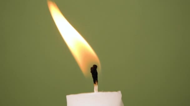 Eine weiße Kerze brennt auf olivem Hintergrund. Eine Kerze wird ausgeblasen, schöner Rauch von einer ausgeblasenen Kerze auf olivem Hintergrund. Video in voller HD-Auflösung in Zeitlupe - Filmmaterial, Video