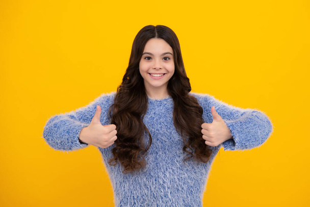 Happy teenager, positive and smiling emotions of teen girl. Happy casual teenager child girl showing thumb up and smiling isolated on yellow background - Photo, Image