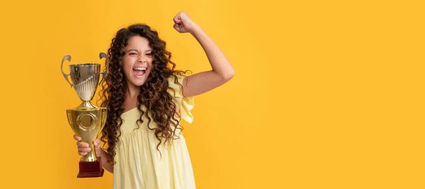 happy teen girl hold golden cup. achievement award. celebrating success and victory. Horizontal poster of isolated child face, banner header, copy space - Photo, Image