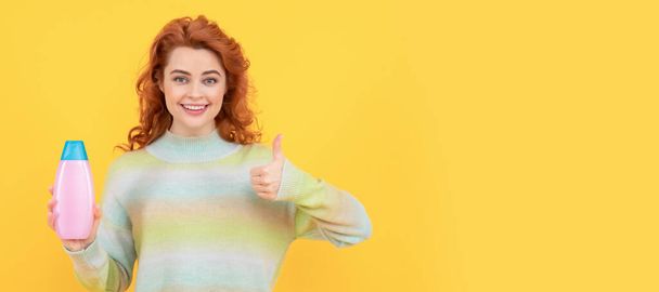 Woman isolated face portrait, banner with copy space. happy redhead woman with curly hair holding shampoo or conditioner showing thumb up, hairdresser - Photo, Image