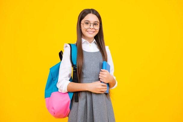 Escola menina segurar Copybook e livro em amarelo isolado estúdio fundo. Conceito de escola e educação. Menina adolescente em uniforme escolar - Foto, Imagem