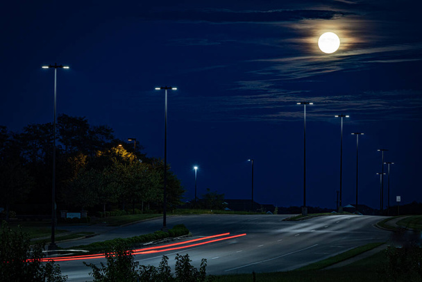 Kirkas kuu yli moottoritien katuvalojen ja polkuja kulkee autoja - Valokuva, kuva