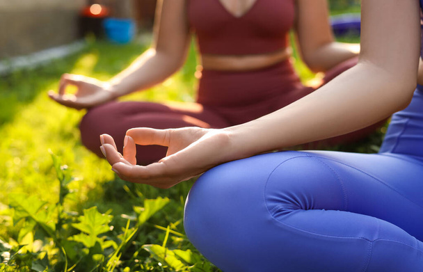 Women meditating on green grass outdoors, closeup. Morning yoga - Fotó, kép