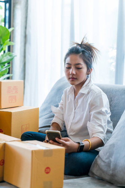 Mulheres asiáticas bonitas sentadas no sofá com muitas caixas de encomendas com pequenas empresas vendem ao cliente em compras on-line. Conceito venda e compras on-line a partir de casa - Foto, Imagem