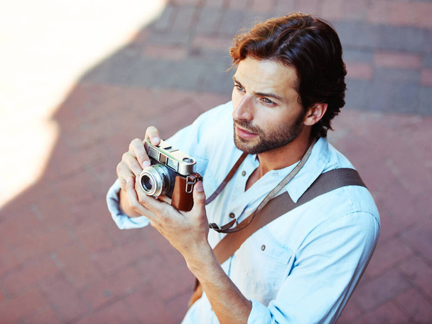 Captura recuerdos. un guapo joven turista sosteniendo su cámara - Foto, imagen