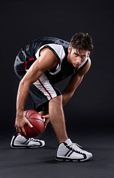 Hard trainen om de beste te zijn. Full length portret van een mannelijke basketbalspeler in actie tegen een zwarte achtergrond - Foto, afbeelding