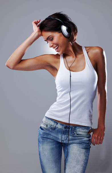Music makes her smile. an attractive young woman listening to music - Фото, изображение