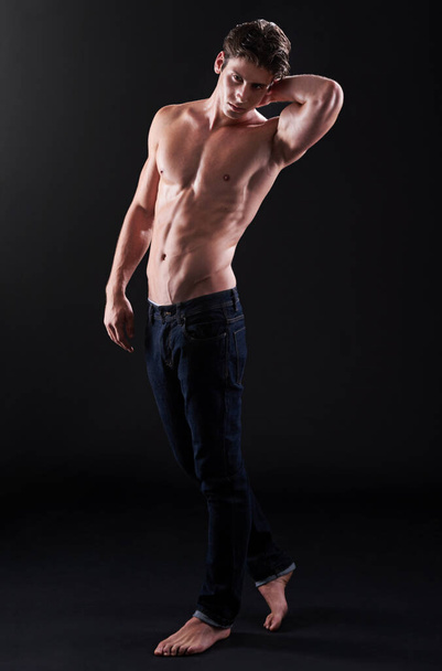 Mira esos abdominales. Captura de estudio de un apuesto atleta joven con el pecho desnudo parado sobre un fondo negro - Foto, imagen