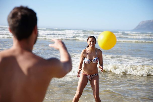 Spending some relaxation time together. a happy couple playing with a ball in the shallow water on the beach - Фото, изображение