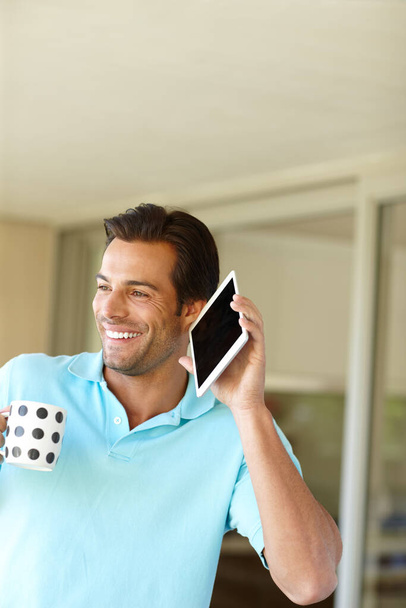 Tartja a kapcsolatot a tabletjével. egy férfi tartja a digitális tabletjét a füléhez kávézás közben. - Fotó, kép