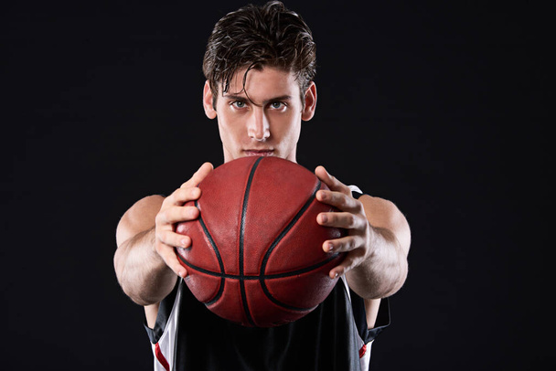 Te reto. Retrato del estudio recortado de un determinado jugador de baloncesto sosteniendo la pelota frente a él - Foto, imagen