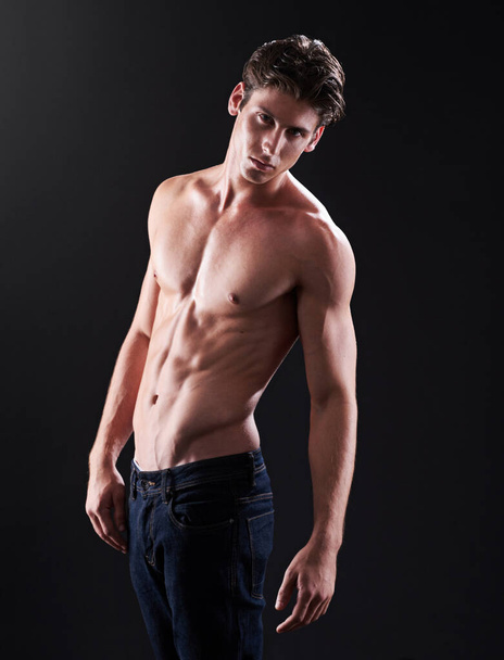 Volkomen mannelijk. Studio shot van een knappe blote borst jonge atleet staan tegen een zwarte achtergrond - Foto, afbeelding