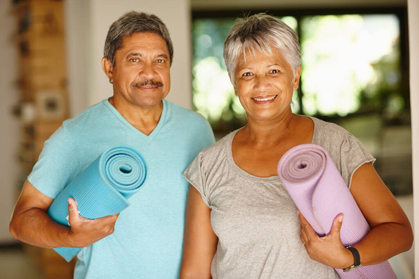 El ejercicio es una parte importante de nuestro día. Retrato de una pareja madura sosteniendo colchonetas de yoga - Foto, imagen