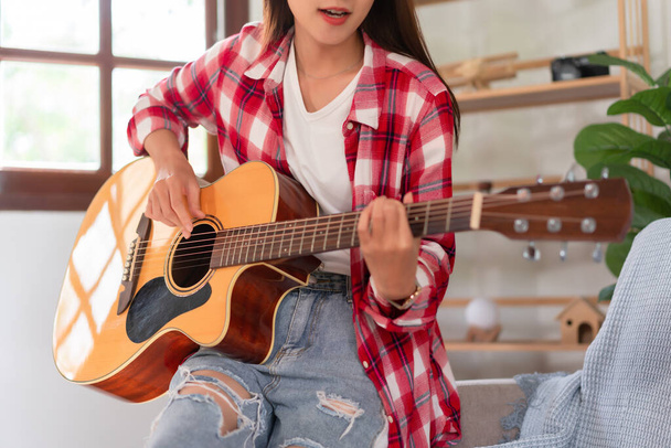 Concept de relaxation avec musique, Jeune femme asiatique pratique des accords de jeu avec guitare acoustique. - Photo, image