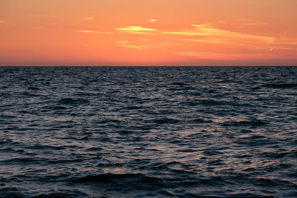 Dramatic bright red sky at ocean sunset, soft evening clouds over sea dark water. - Φωτογραφία, εικόνα