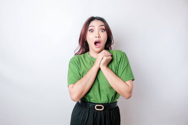 A portrait of a shocked Asian woman wearing a green t-shirt, isolated by a white background - Valokuva, kuva