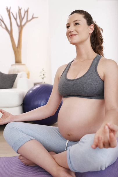 She knows this hard work will pay off. a young pregnant woman exercising at home - Foto, Imagen