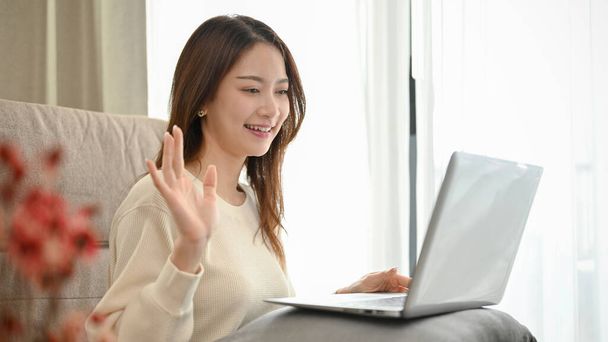 Çekici Asyalı kız ya da üniversite öğrencisi oturma odasında oturmuş arkadaşlarından ya da dizüstü bilgisayarla online görüşme yapıyor.. - Fotoğraf, Görsel