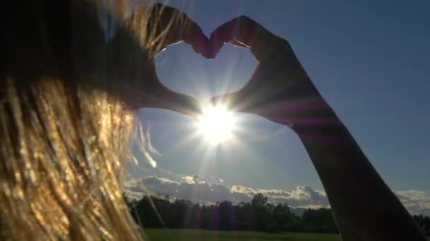 Mujer atrapando el sol en las manos en forma de corazón
 - Metraje, vídeo