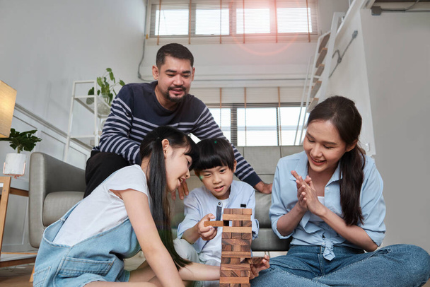 Happy Asian lovely Thai family activity, parents, dad, mum, and children have fun playing and joyful wooden toy blocks together on living room floor, leisure weekend, and domestic wellbeing lifestyle. - Fotografie, Obrázek