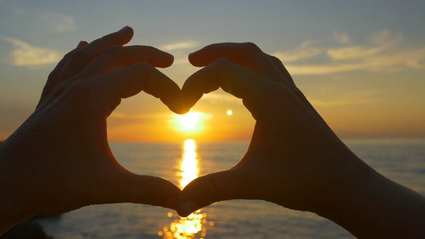 Szív alakú kezével naplementében - Felvétel, videó